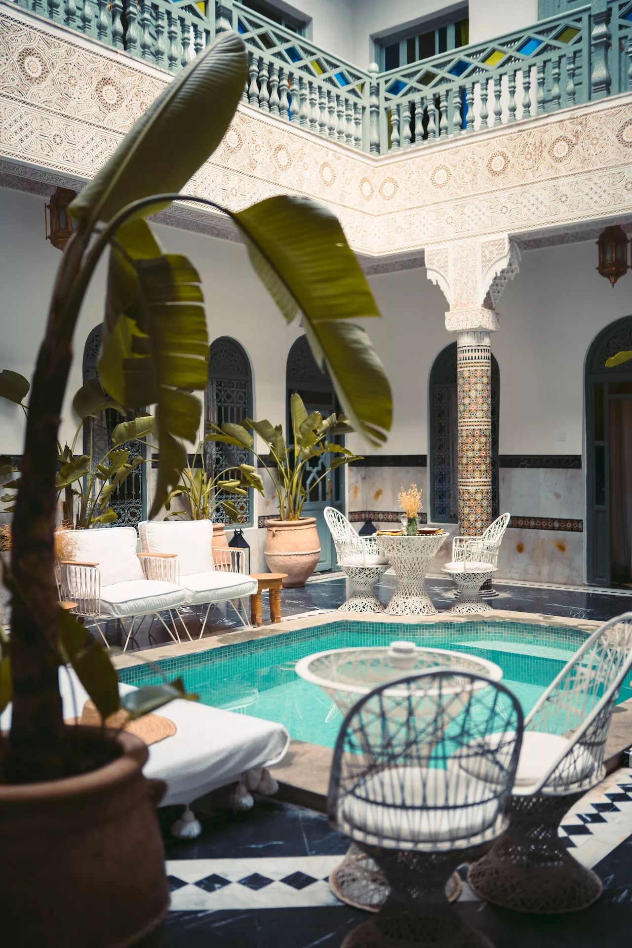 Riad courtyard with small pool, banana plants and painted shutters