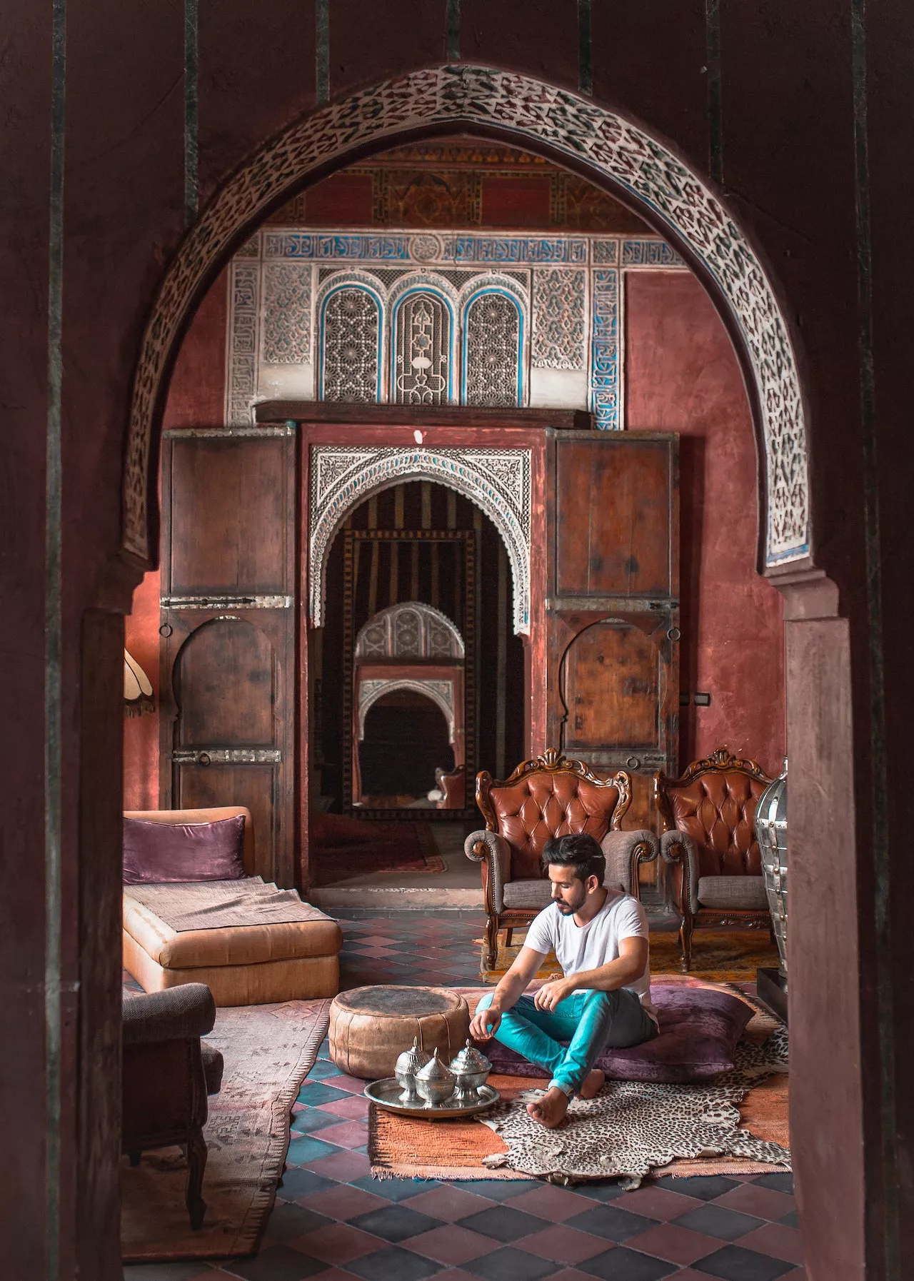 Traveller sitting in the carved doorway of a riad salon, Marrakech