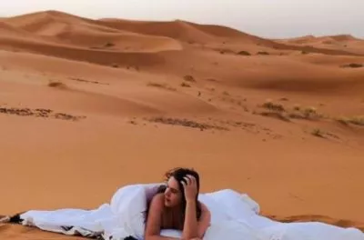 Woman resting on a bed set up on the dunes at a Sahara desert camp