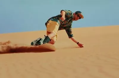 Sandboarder sliding down a dune at Merzouga, Morocco
