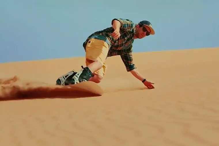 Sandboarder sliding down a dune at Merzouga, Morocco
