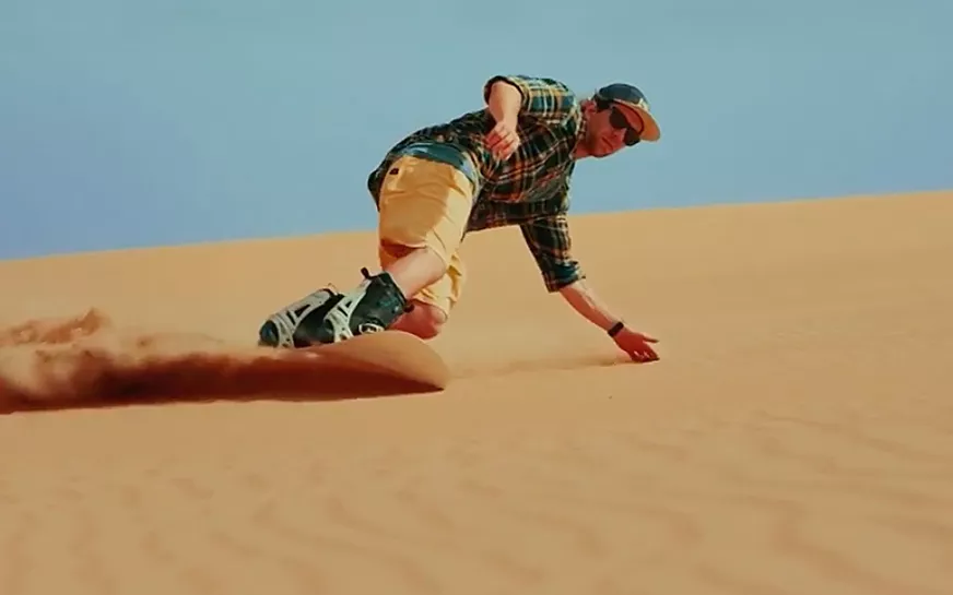 Sandboarder sliding down a dune at Merzouga, Morocco
