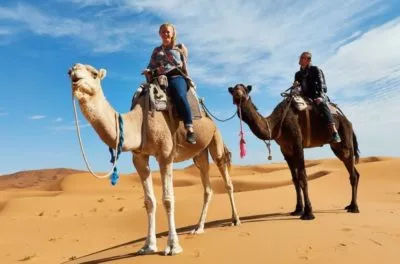 Two riders on camels crossing the dunes at Merzouga, Morocco