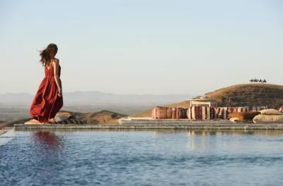 Woman in a red dress beside the pool of an Agafay desert camp, Marrakech