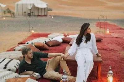 Couple relaxing on cushions outside a luxury desert camp tent, Morocco