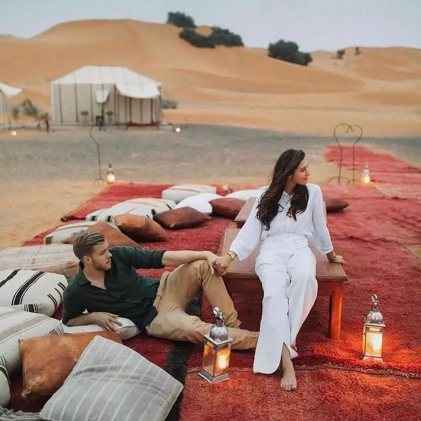 Couple relaxing on cushions outside a luxury desert camp tent, Morocco