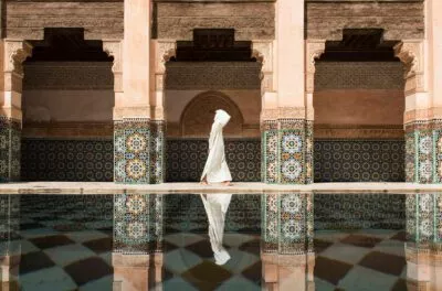 Visitor in a white djellaba beside the pool of Ben Youssef Madrasa, Marrakech