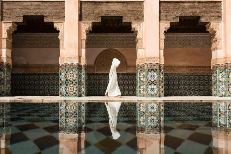 Visitor in a white djellaba beside the pool of Ben Youssef Madrasa, Marrakech
