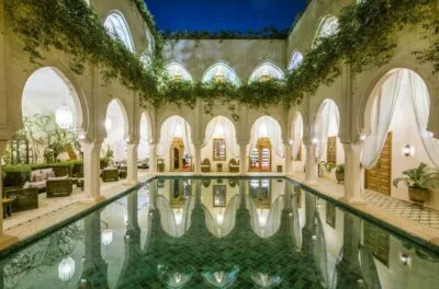 Riad courtyard pool with arches and climbing plants, Fes