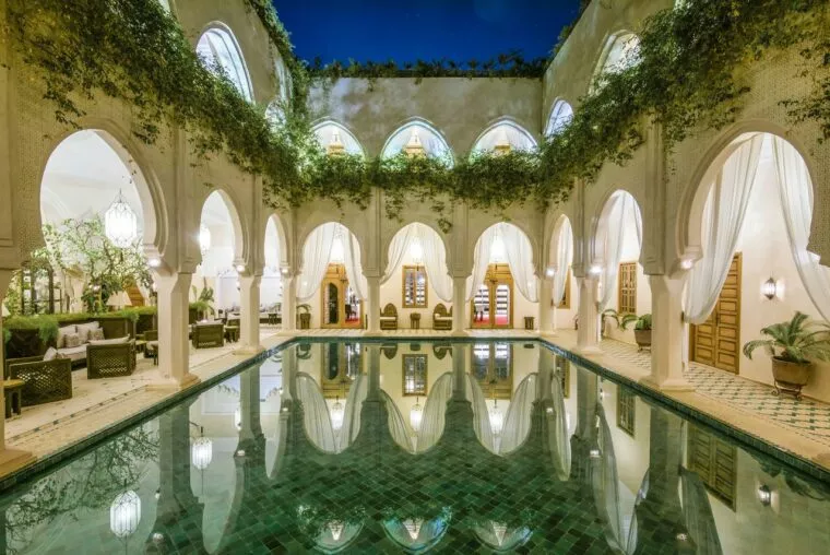 Riad courtyard pool with arches and climbing plants, Fes