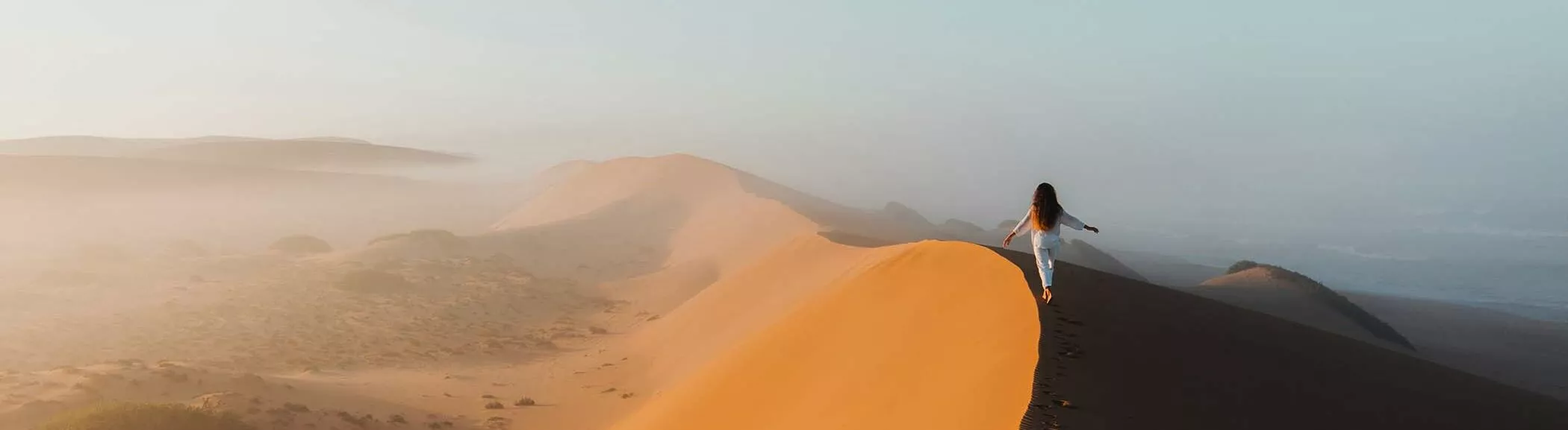 Person walking along a dune crest in the Sahara, Morocco